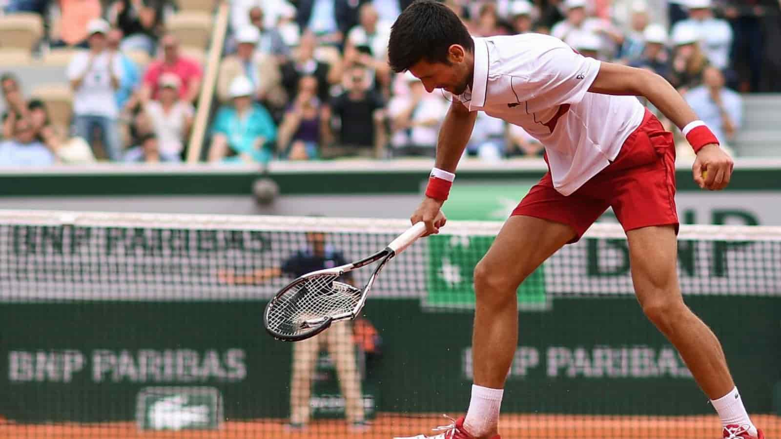 Novak Djokovic smashes his racquet while practicing with Alexander Zverev at the 2020 Tokyo Olympics