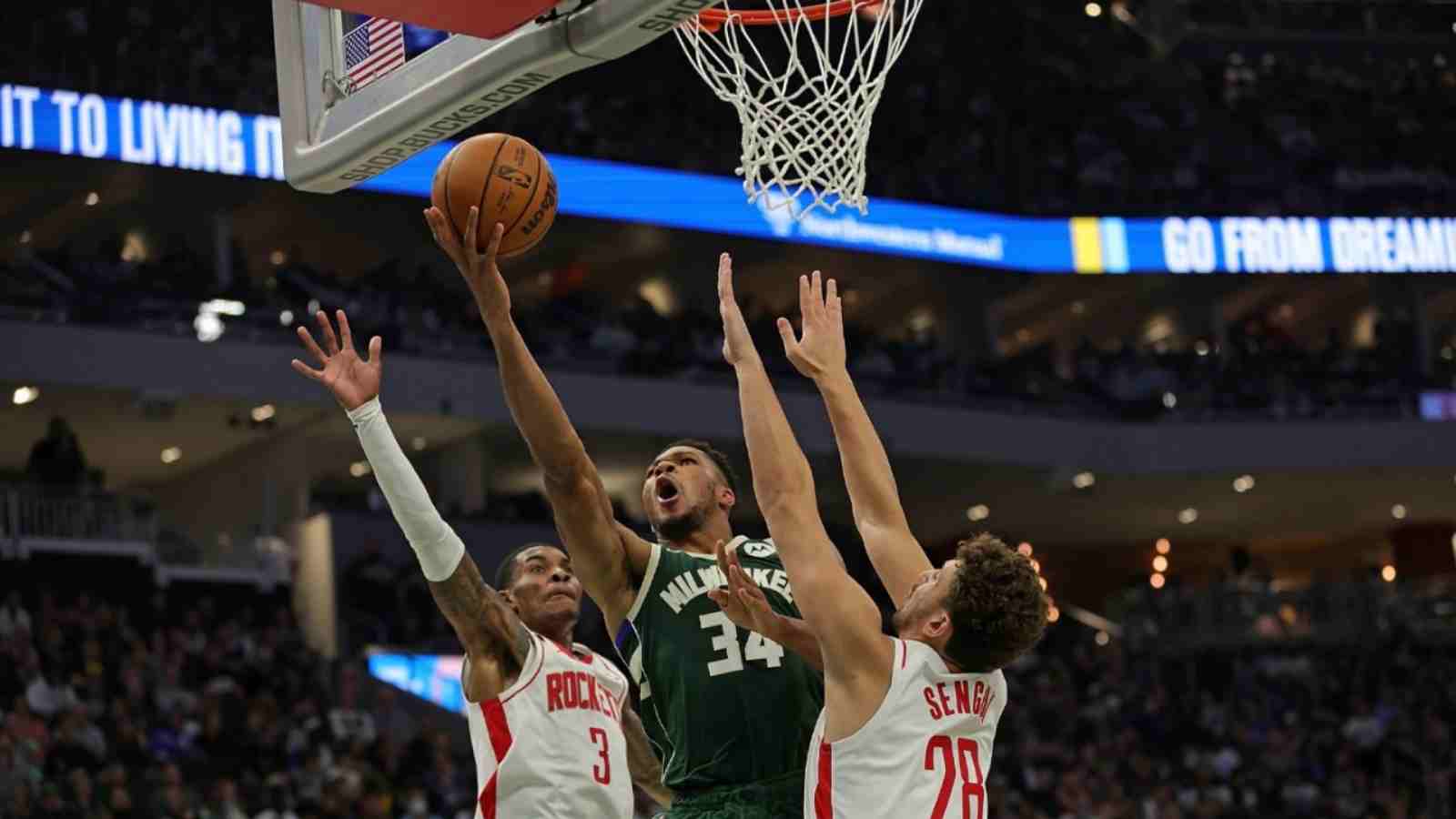 Giannis Antetokounmpo drives to the basket past two Rockets' defenders