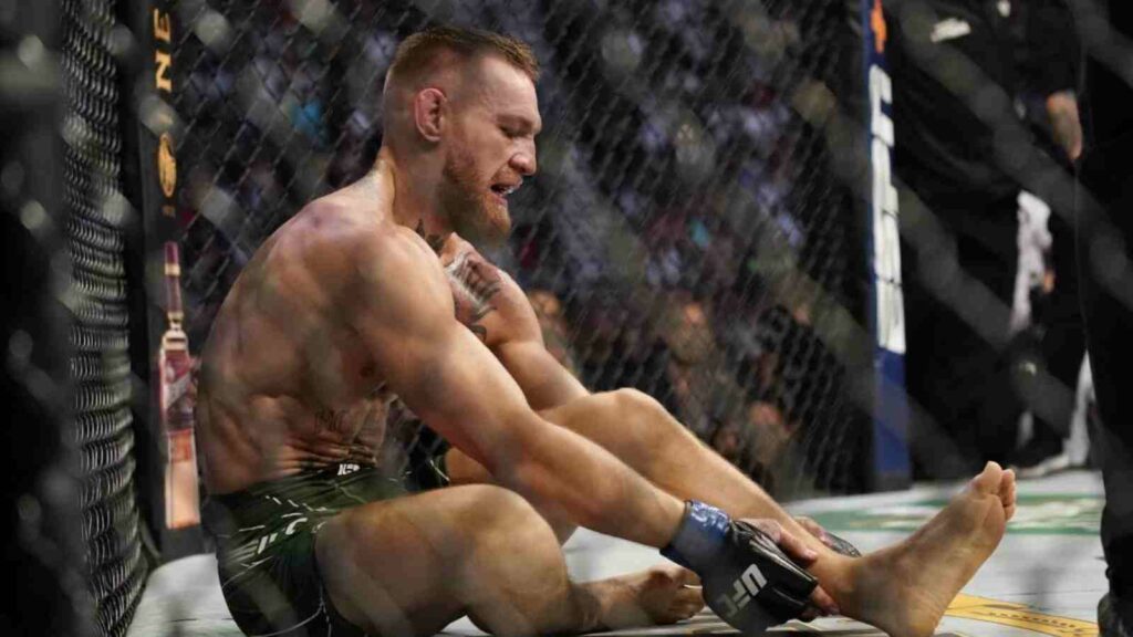 Conor McGregor (R) looks sullen after breaking his leg against Dustin Poirier in 2021