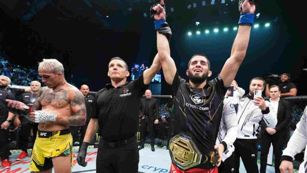 A sullen Charles Oliveira (L) unwraps his gloves as Islam Makhachev (R) beats him to the lightweight belt